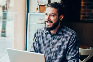 Smiling male on Laptop at Coffee shop - Express Your Gratitude Image