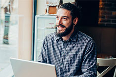 Smiling male on Laptop at Coffee shop - Express Your Gratitude Image